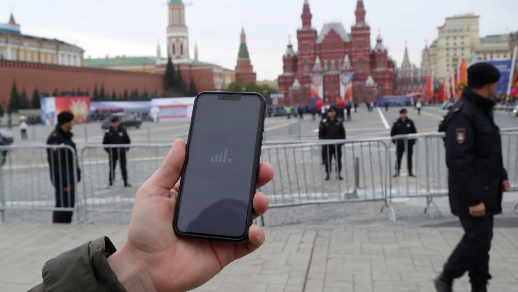 A person is standing in Moscow city center, holding their phone which shows no mobile internet connection