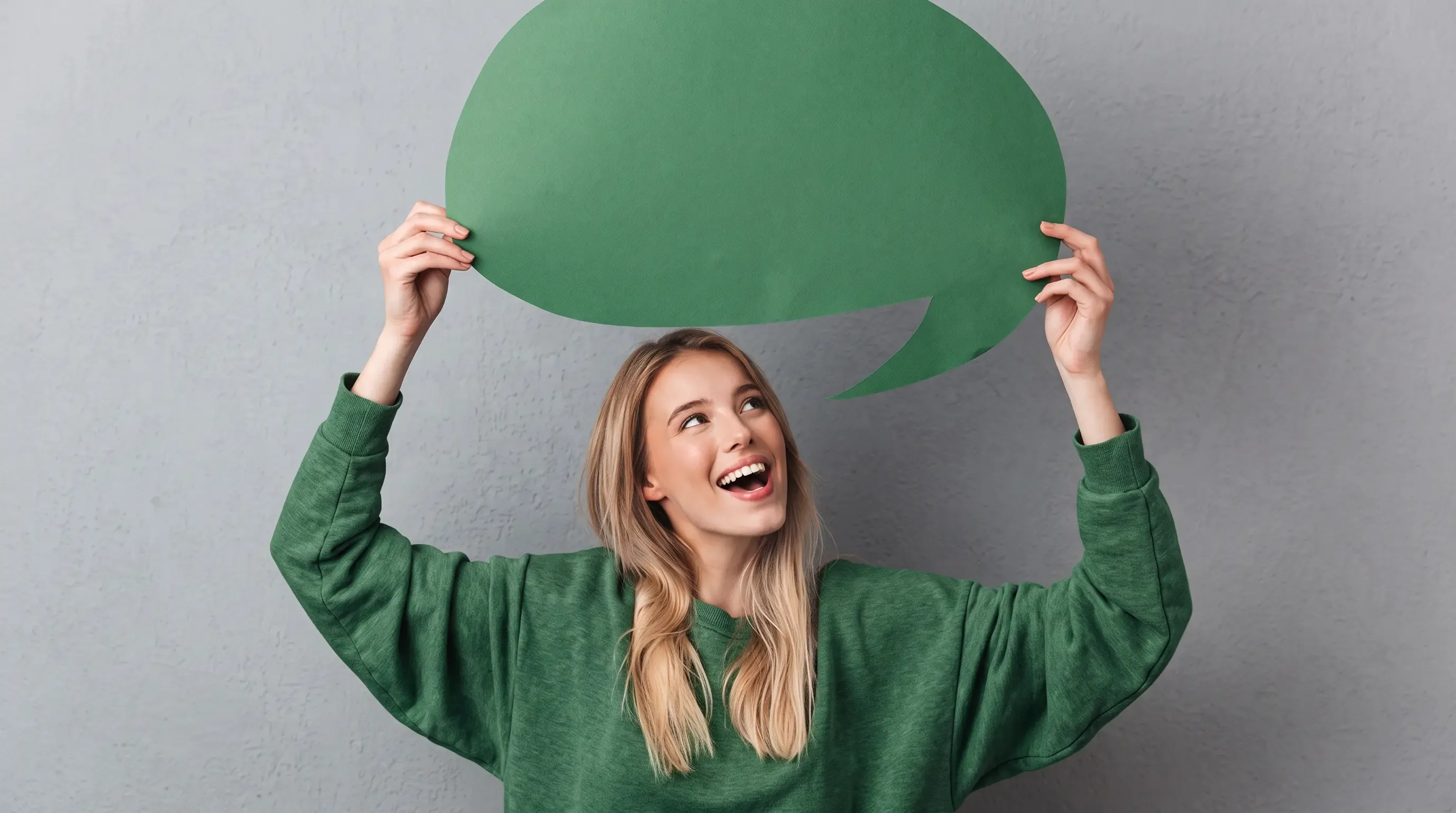 A happy woman holding up a giant paper speech bubble