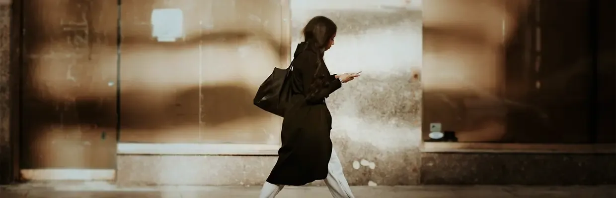 An image of a woman walking down the street looking at her phone